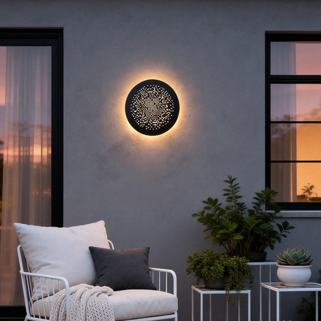 Perforated metal wall sconce mounted on an exterior wall beside outdoor seating.