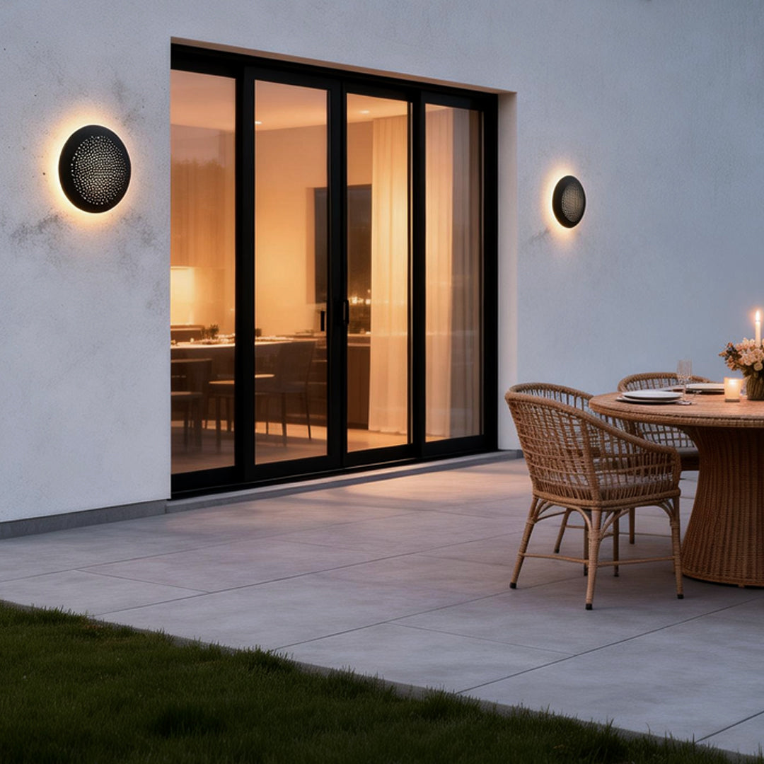 Perforated metal wall sconce installed on a modern patio wall near sliding doors.