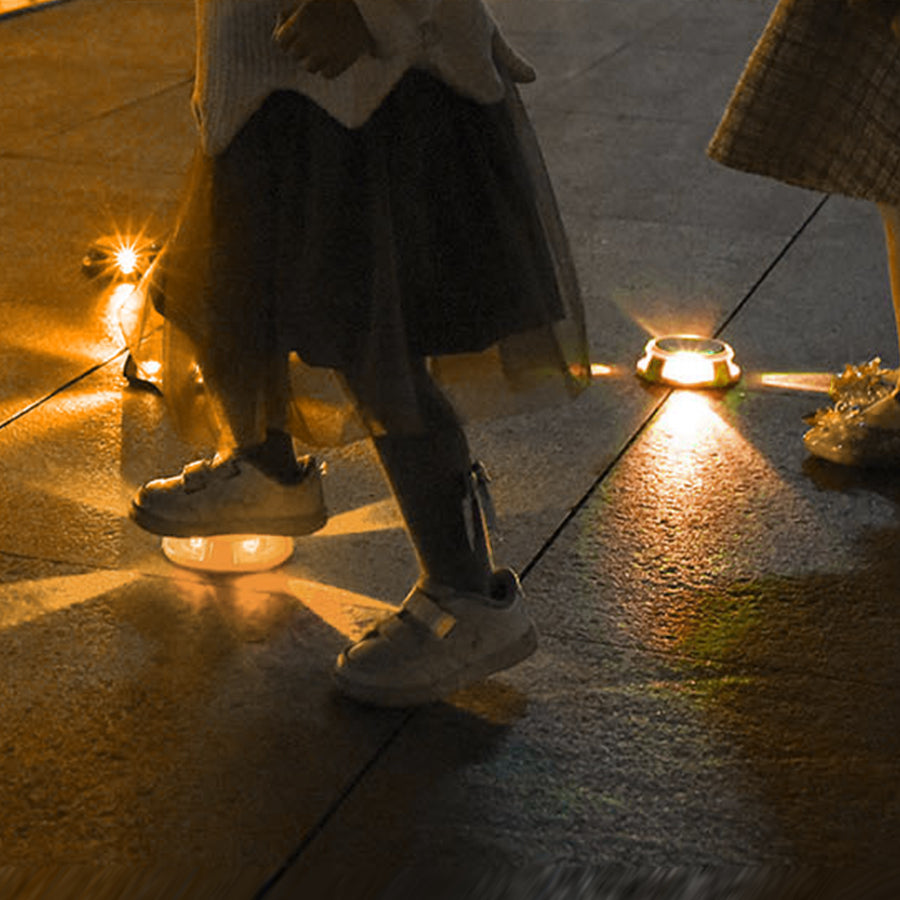 Person walking on illuminated pathway with embedded solar ground lights providing safety lighting