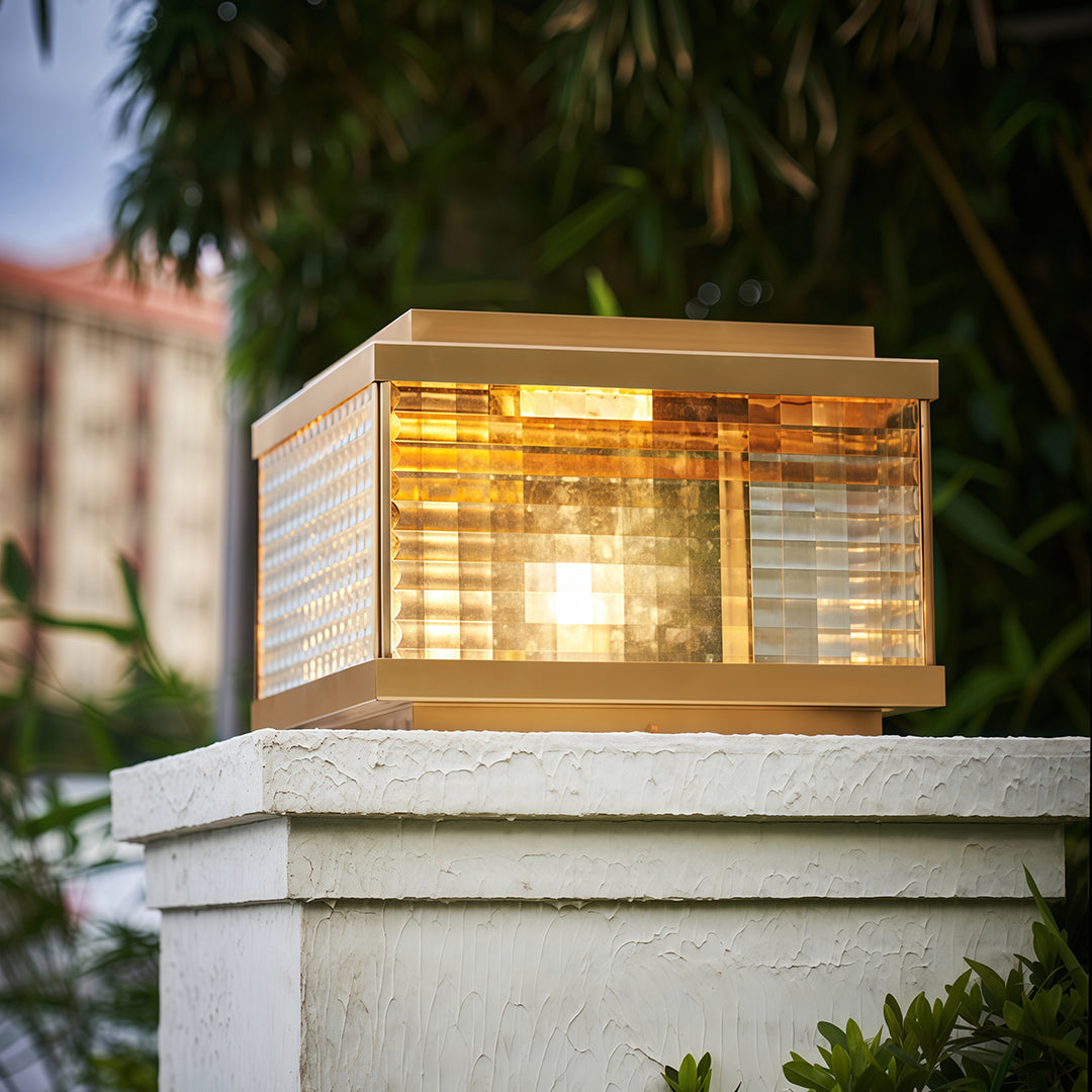 Pillar cap lights mounted on white stone column beside residential entrance with natural garden setting
