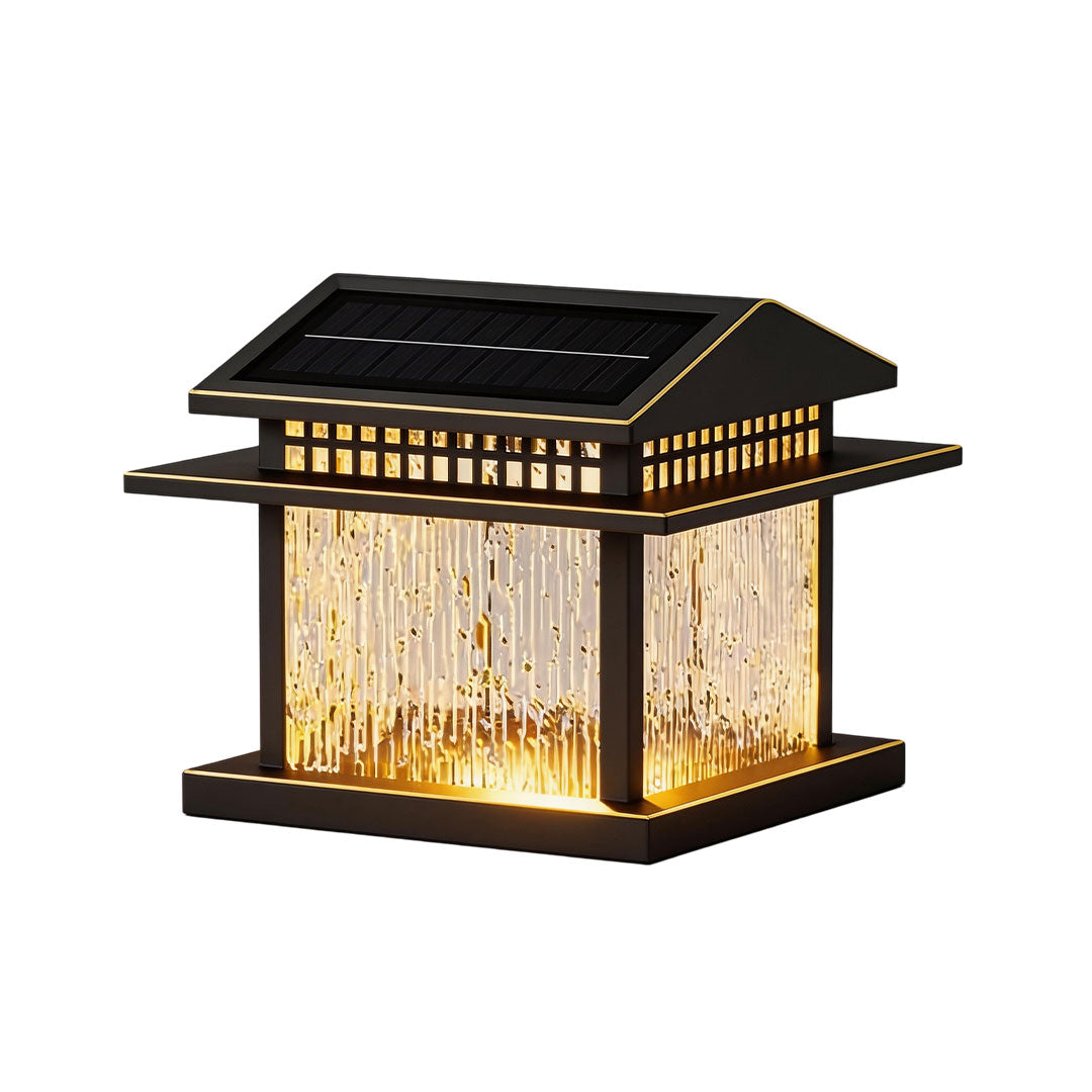 Modern pillar lamp light with glass panels and black frame, illuminated in a cozy outdoor setting.