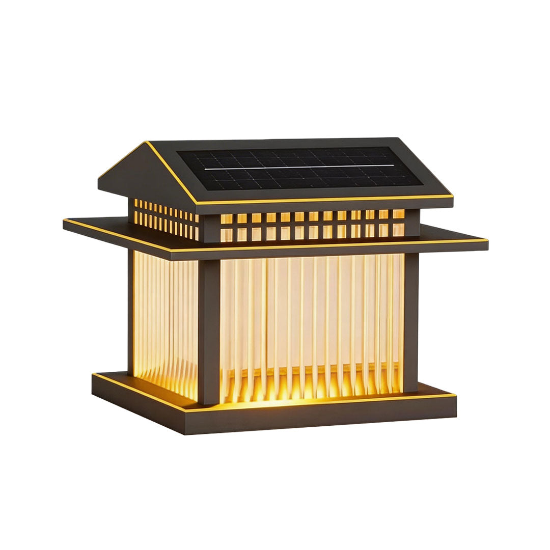 Decorative pillar lamp light with intricate glass design, casting a warm glow outdoors.