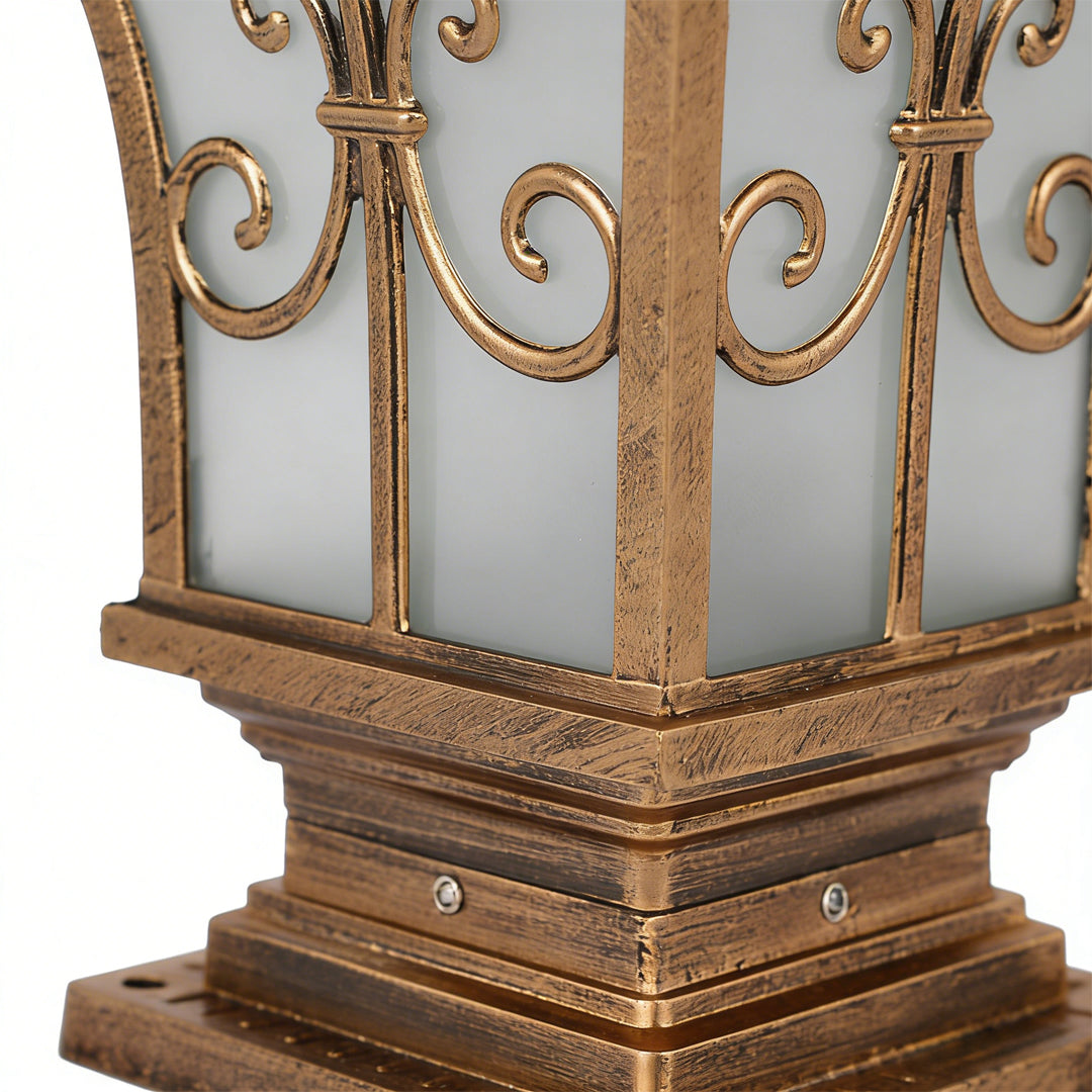 Pillar lantern lights with a decorative bronze finish, installed on a stone pillar.