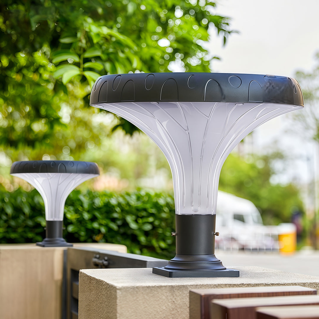 Pillar light fixture standing near a decorative garden gate, casting a welcoming glow.