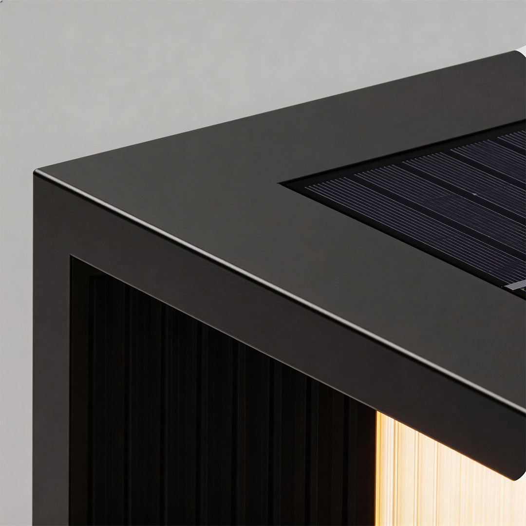 Close-up of pillar lighting with a black finish and illuminated top for outdoor pathways.