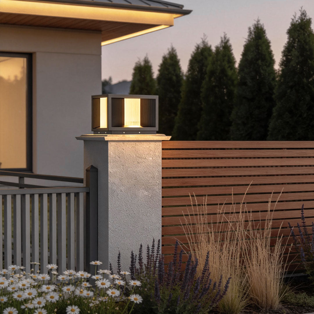 Elegant pillar lighting mounted on stone pillars beside a contemporary house with wooden accents.