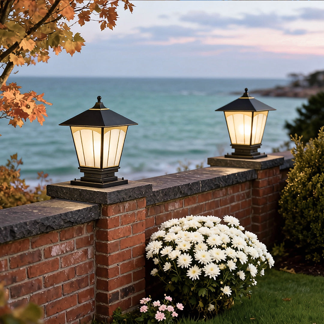 Pillar lights for house providing soft illumination beside a seaside wall at dusk.