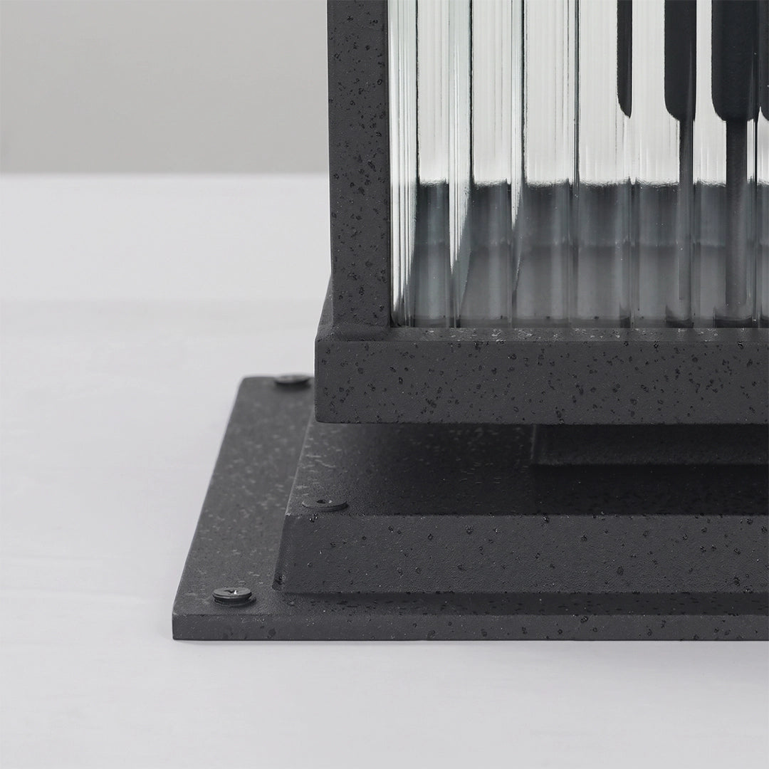 Close-up of the base and ribbed glass panels on a black pillar solar light.