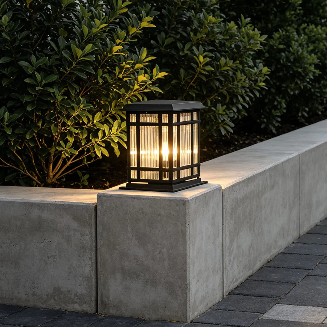 Pillar solar light placed on a concrete garden wall beside shrubs for warm outdoor accent lighting.