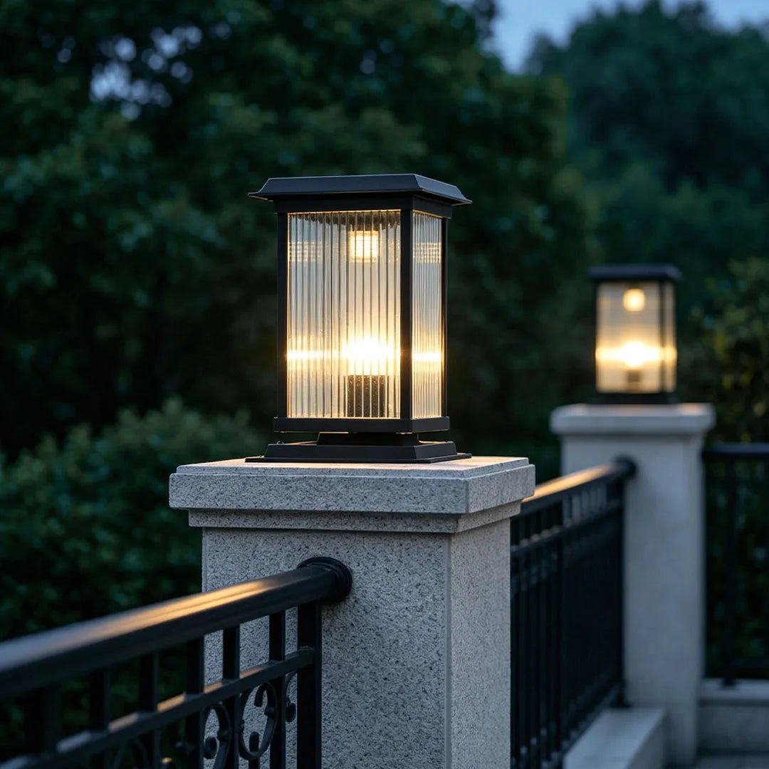 Pillar solar light installed on fence posts, providing warm illumination along an outdoor railing at dusk.