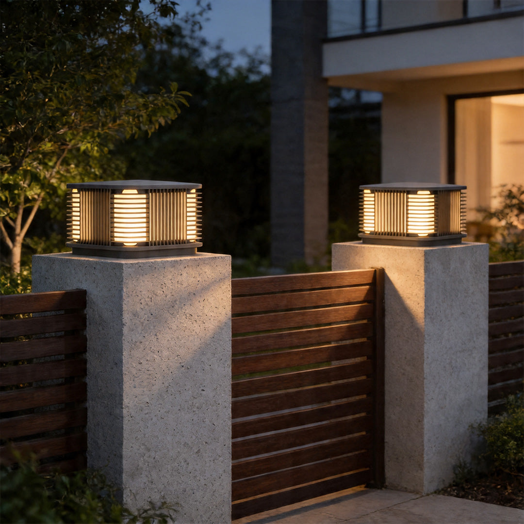 Pillar solar lights installed on modern entrance posts with warm outdoor gate lighting at night.