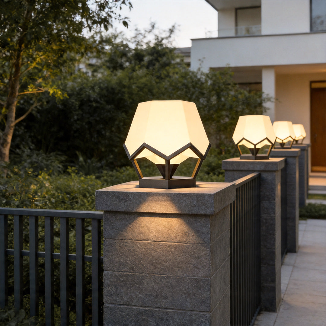 Pillar top solar lights illuminating modern stone gate posts with warm ambient outdoor glow.