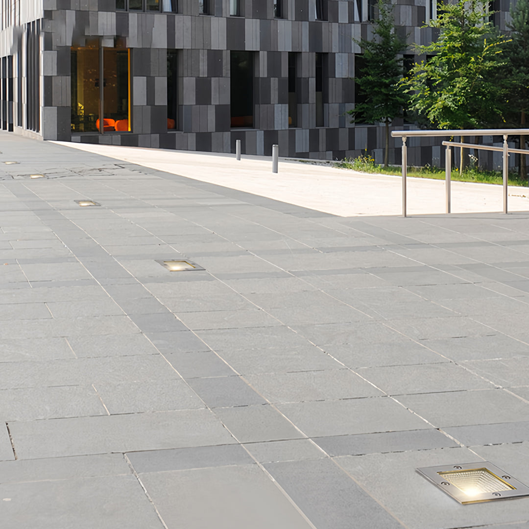 Large outdoor plaza with multiple square outdoor inground lighting fixtures embedded in pavement.