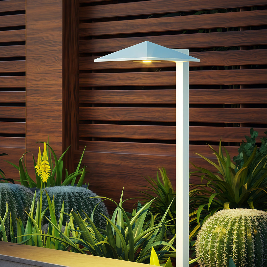 Plug-in pathway light in a garden with plants, adding a contemporary touch to the outdoor space.