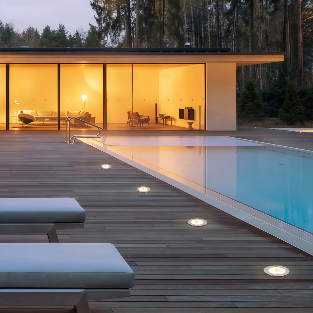 Inground light installed beside a pool deck creating ambient landscape and pathway illumination.