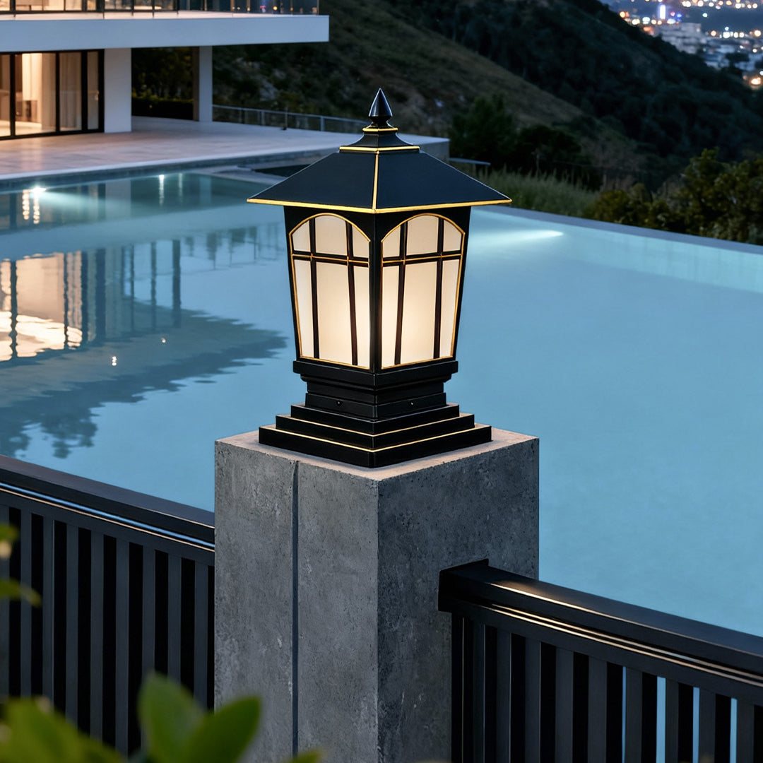 Large outdoor pillar lights mounted near a poolside fence with bright warm glow.