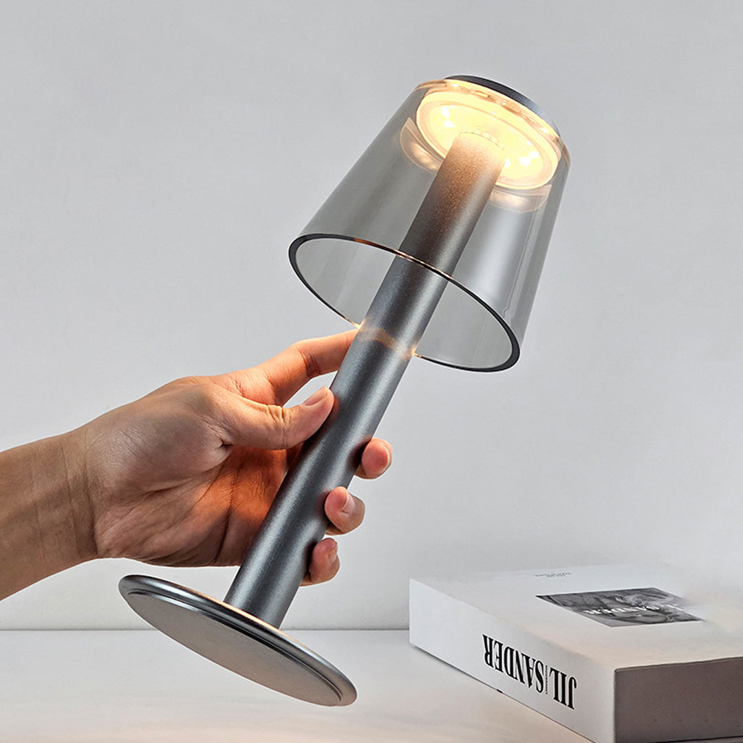 Portable adjustable table lamp being held to demonstrate flexible positioning and compact design