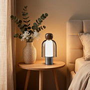 Portable glass table light illuminating a cozy bedside table with warm, ambient glow.