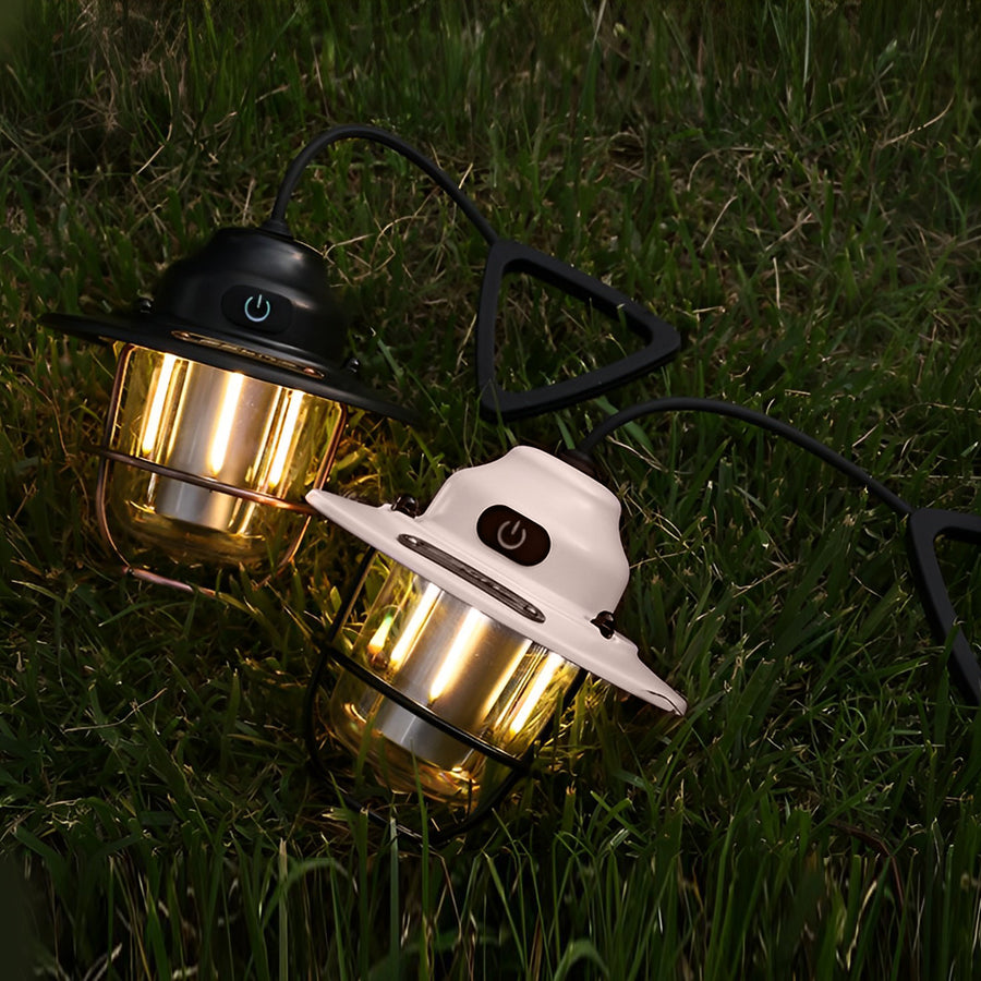 Portable hanging light with a white finish, casting a soft glow on the grass.