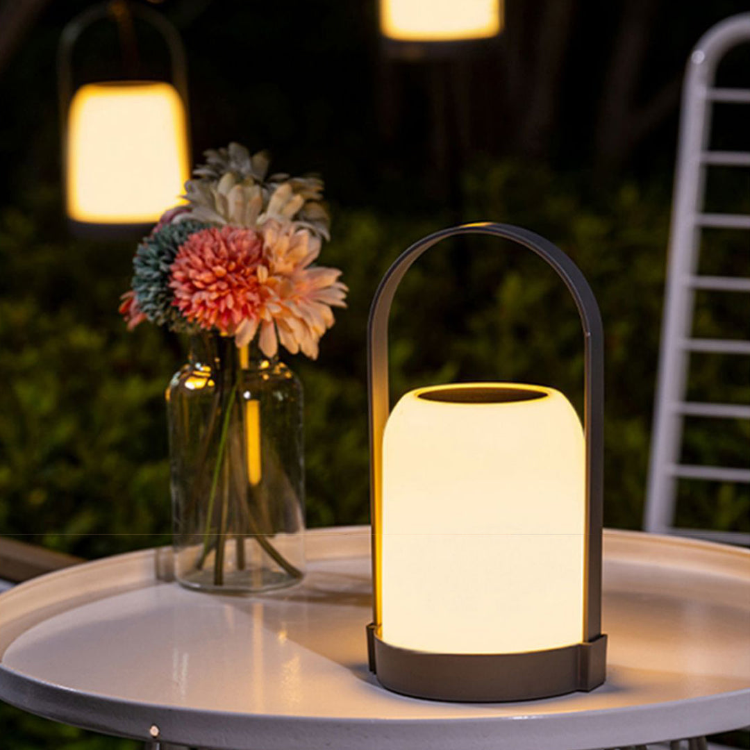Elegant portable lantern with soft glow positioned on dining table with flowers and garden view
