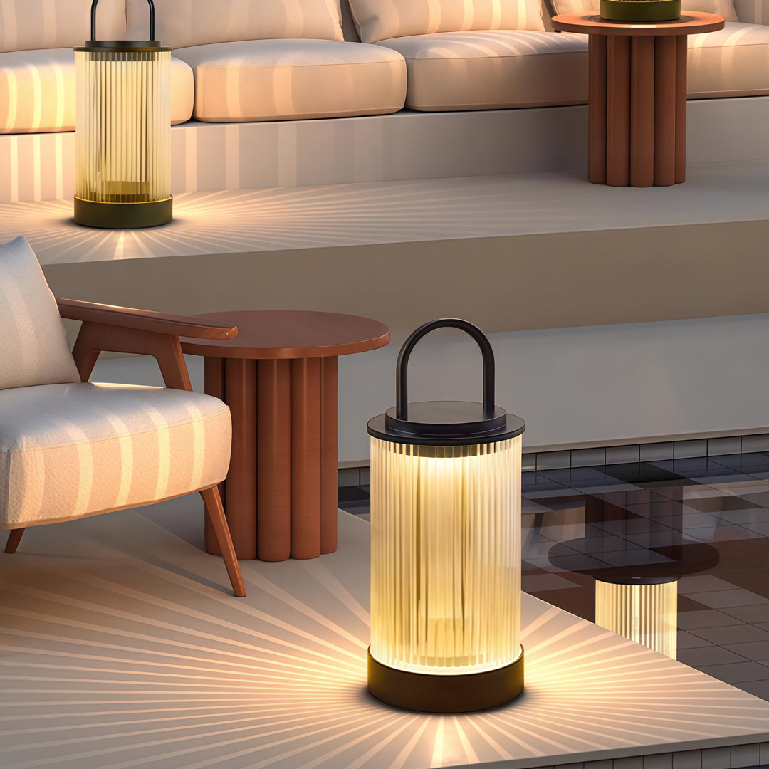 Contemporary outdoor portable lantern illuminating a patio seating area with soft warm glow.