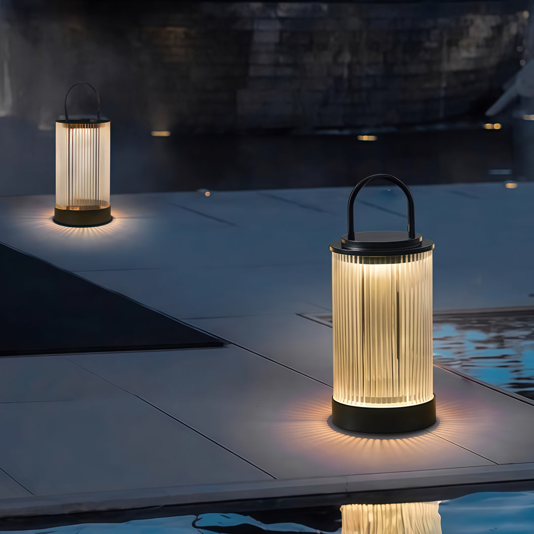 Two portable lanterns showcased on a white background featuring ribbed glass and metal handle.