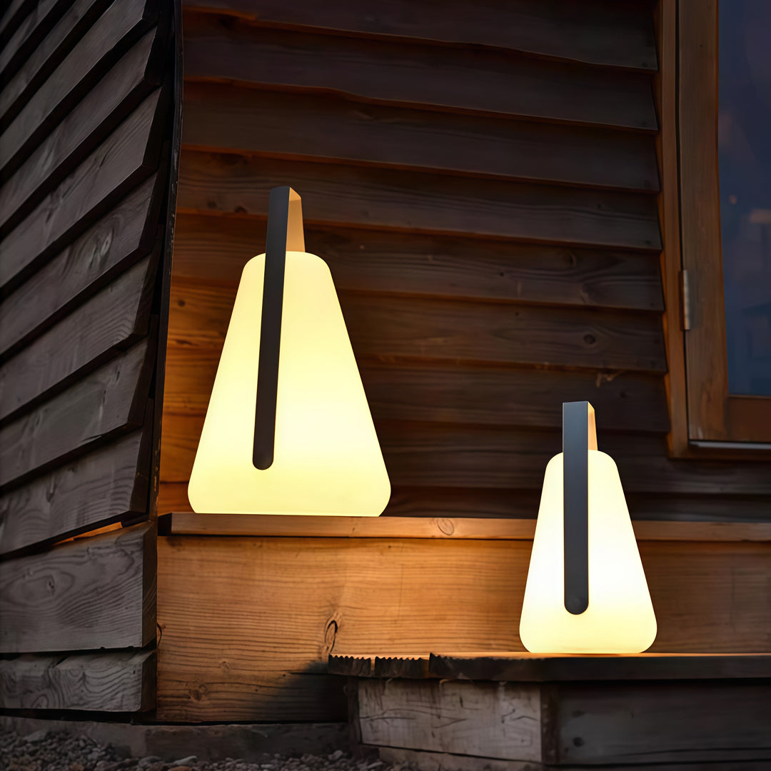 A set of portable led lanterns placed near a wooden exterior wall, creating a cozy and warm nighttime outdoor mood.