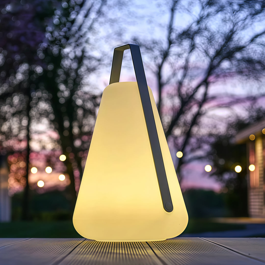 A single illuminated portable led lantern standing on grass at sunset, adding soft and portable ambient lighting.