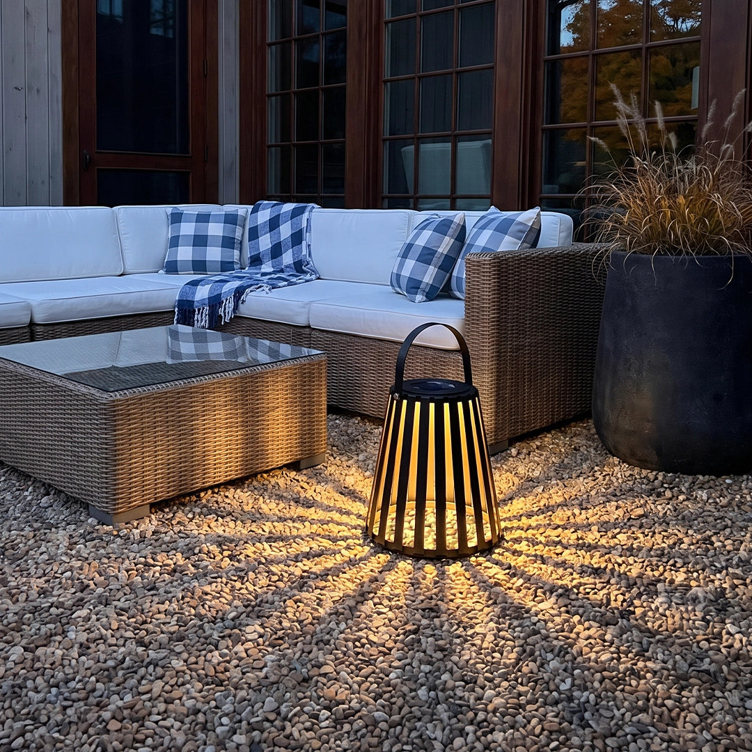 Portable LED light lantern casting warm striped light beside outdoor patio seating.