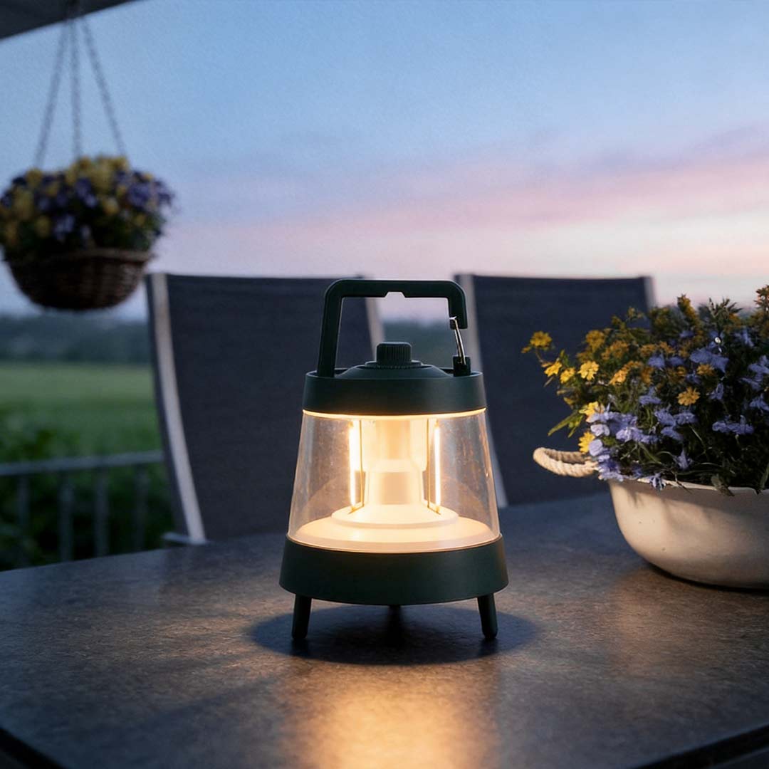 Portable rechargeable LED lamp with a sleek design, placed beside potted plants.