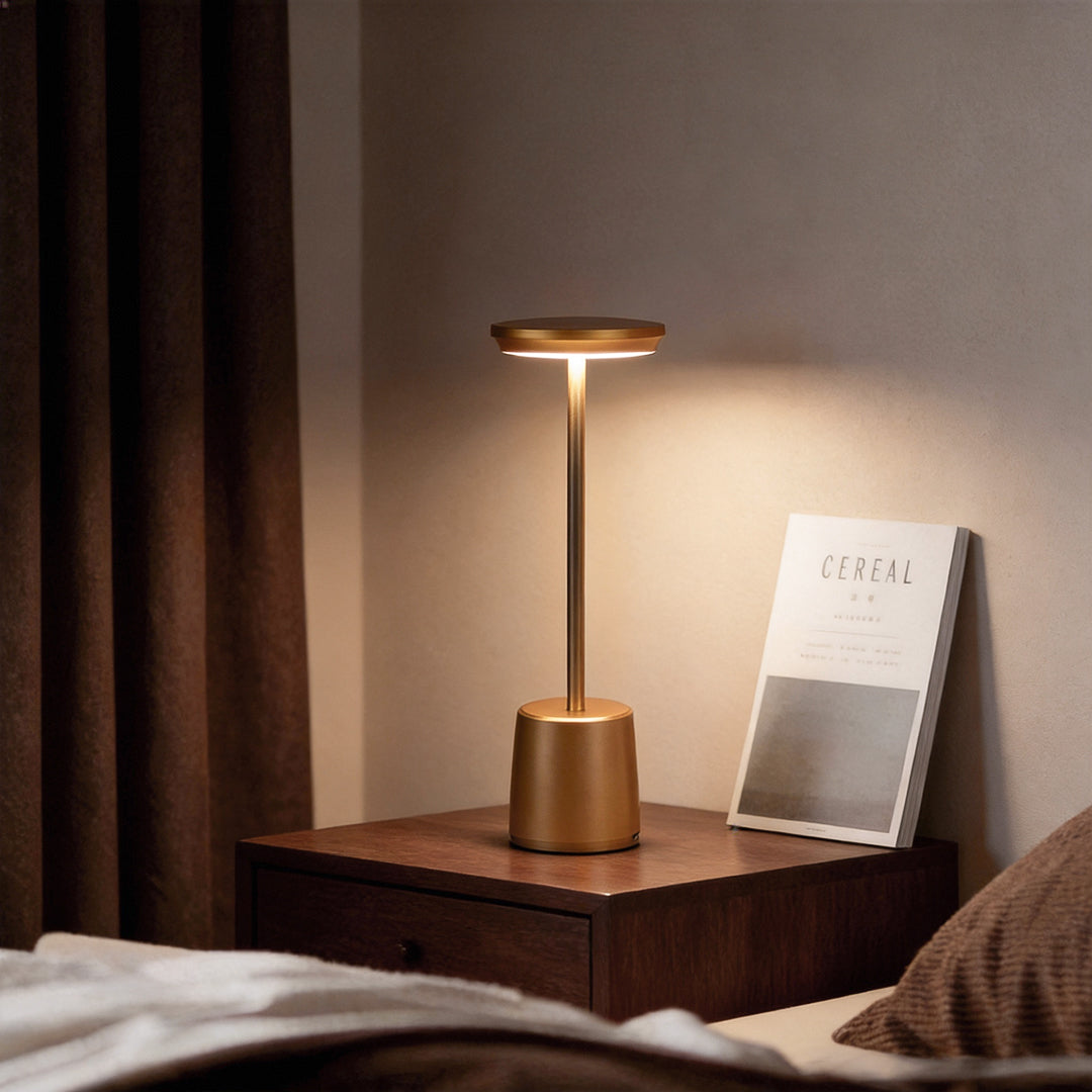 Portable rechargeable LED table lamp illuminating a cozy bedside table with warm, soft glow.