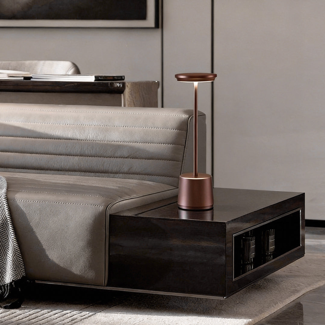 Portable rechargeable LED table lamp providing focused light beside a modern sofa.