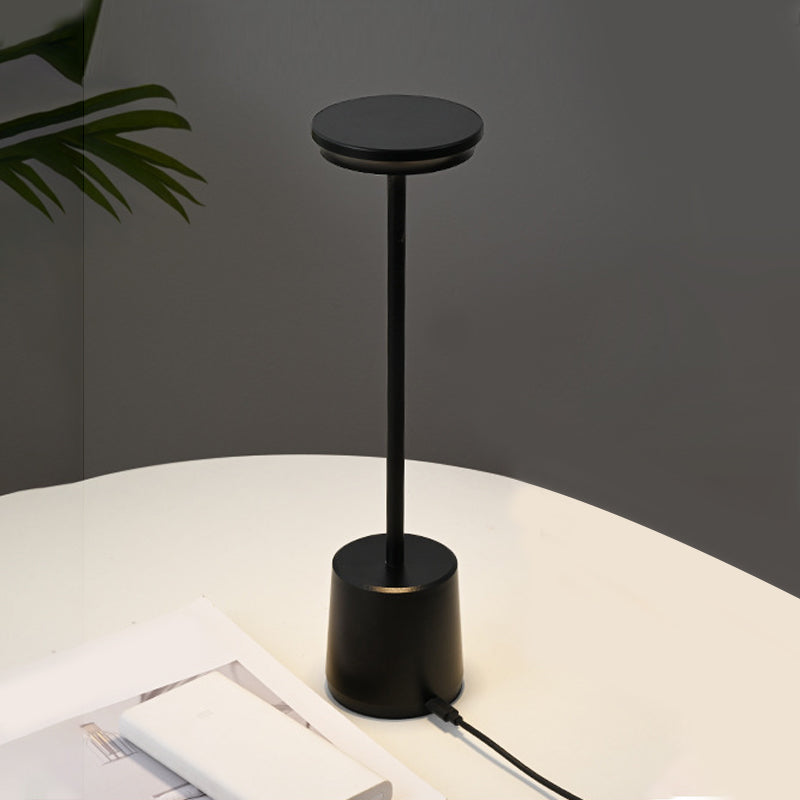 Portable rechargeable LED table lamp casting a gentle glow on a white desk.
