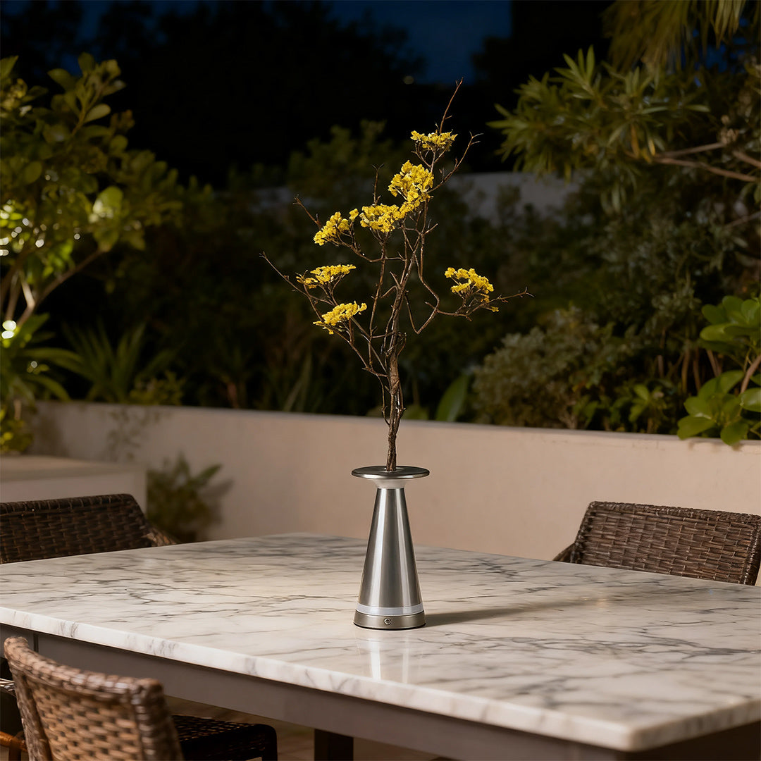 Portable silver vase table lamp on an outdoor marble table at night, acting as a centerpiece.