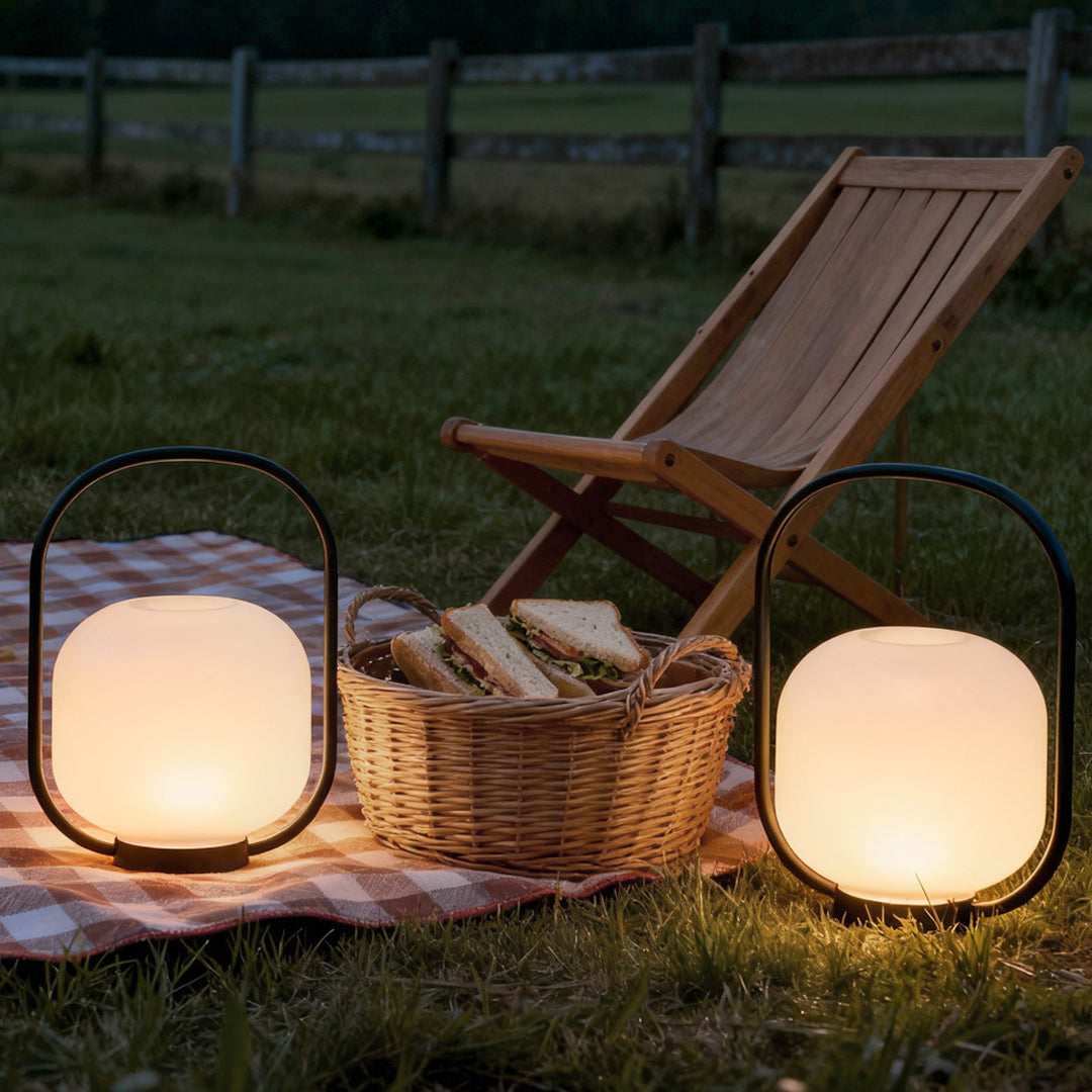 Portable solar lantern beside a picnic basket, adding warm light to a garden picnic setting.