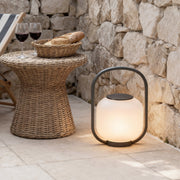 Portable solar lantern placed on a stone table, creating a cozy ambiance for an outdoor dining setup.