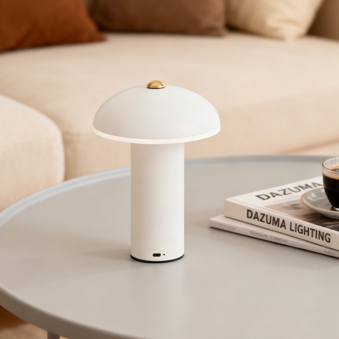 Portable white dimmable LED table lamp on a round coffee table next to reading materials in a contemporary living room.