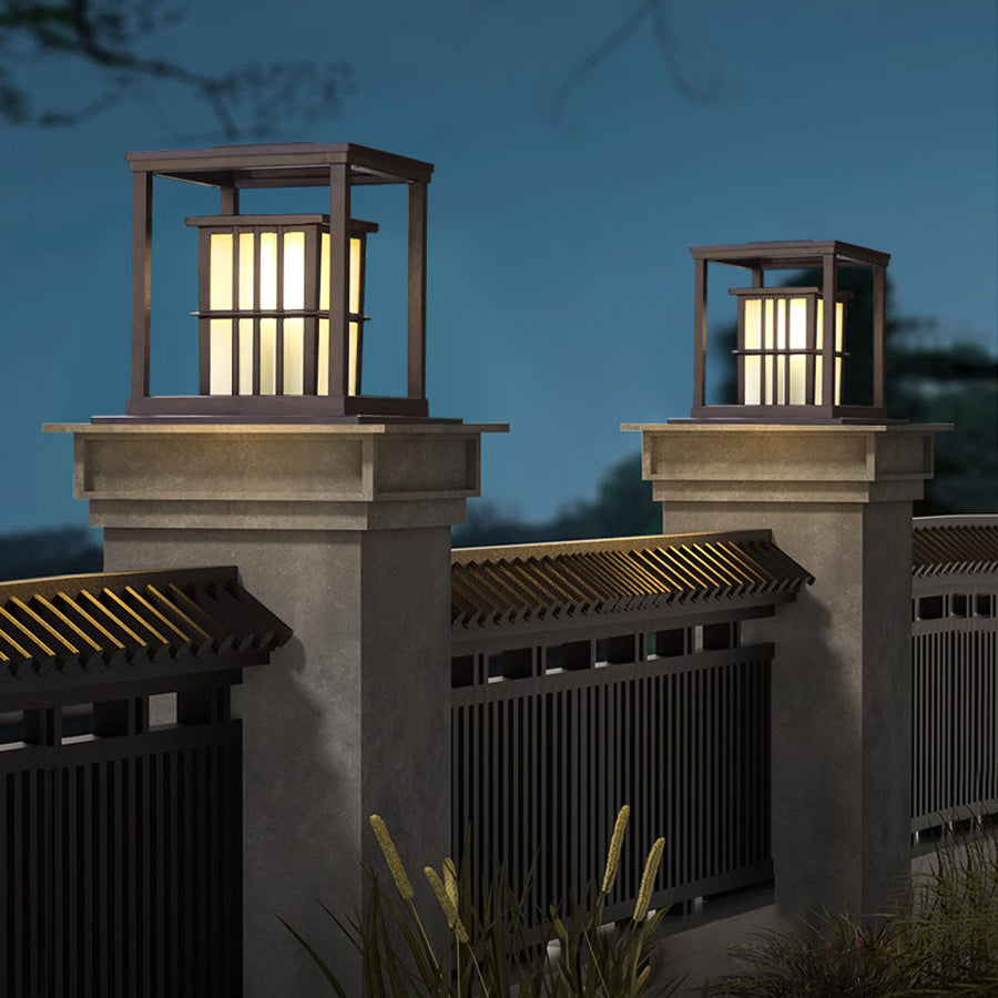 Two elegant post cap lights with vertical bar design illuminating concrete pillars at evening