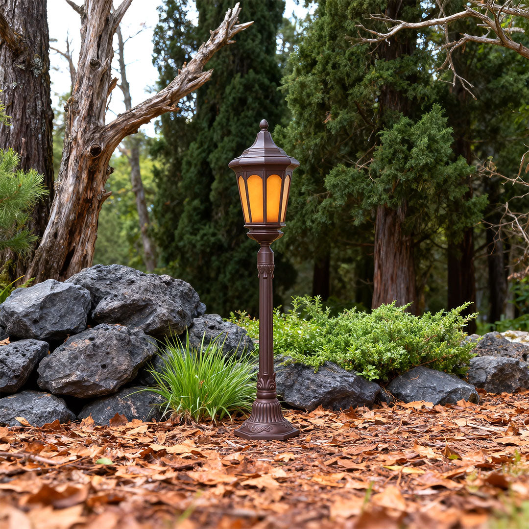 Post path light brightening rock garden landscaping with natural stone and greenery at dusk