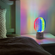 Decorative colourful table lamps with prismatic effect illuminating modern bedroom nightstand setup