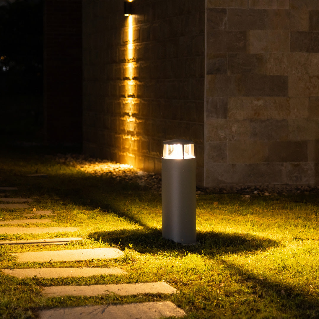 Professional landscape lighting installation with bollards illuminating paved walkway at night