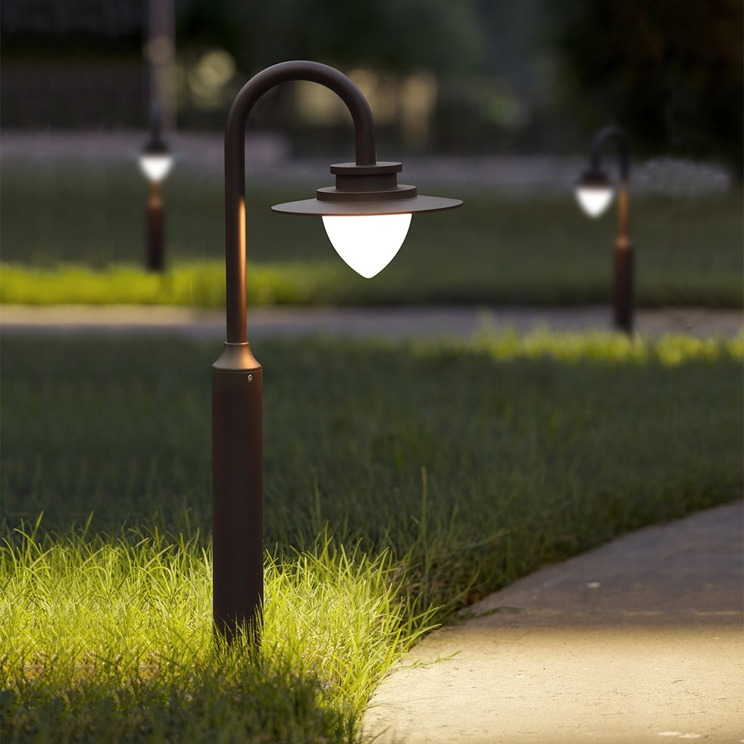 Professional landscape lighting installation with curved bollard lights along concrete walkway