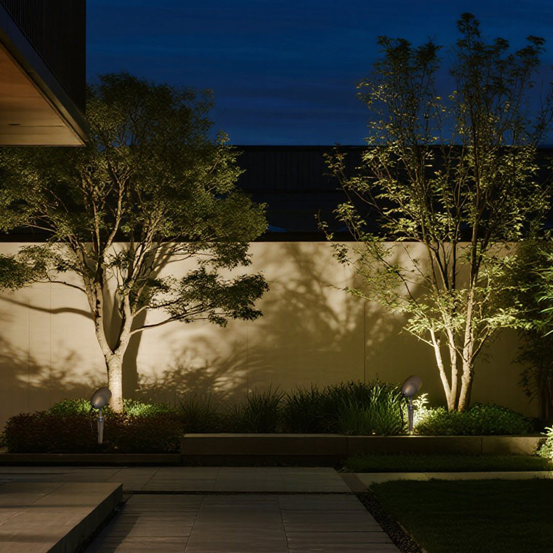 Professional outdoor lighting showcasing garden plantings with dramatic uplighting effects