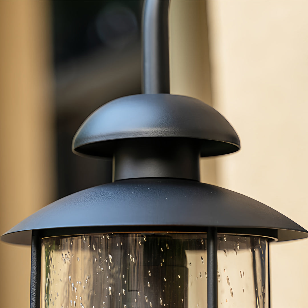 Outdoor wall mount light fixtures with black dome top and raindrop-textured glass.