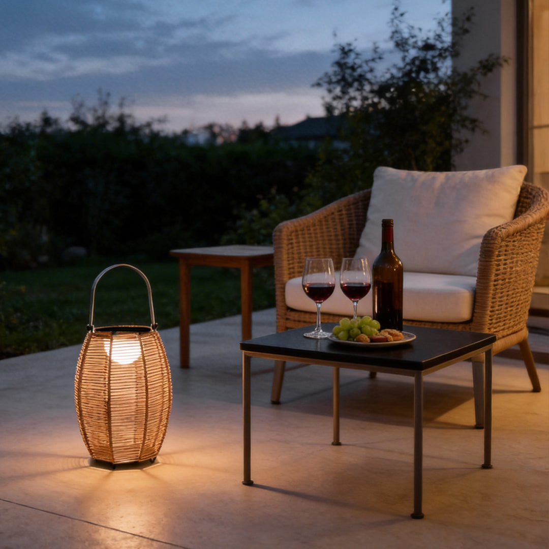 Rattan floor lantern illuminating a cozy outdoor seating area with warm ambient glow.