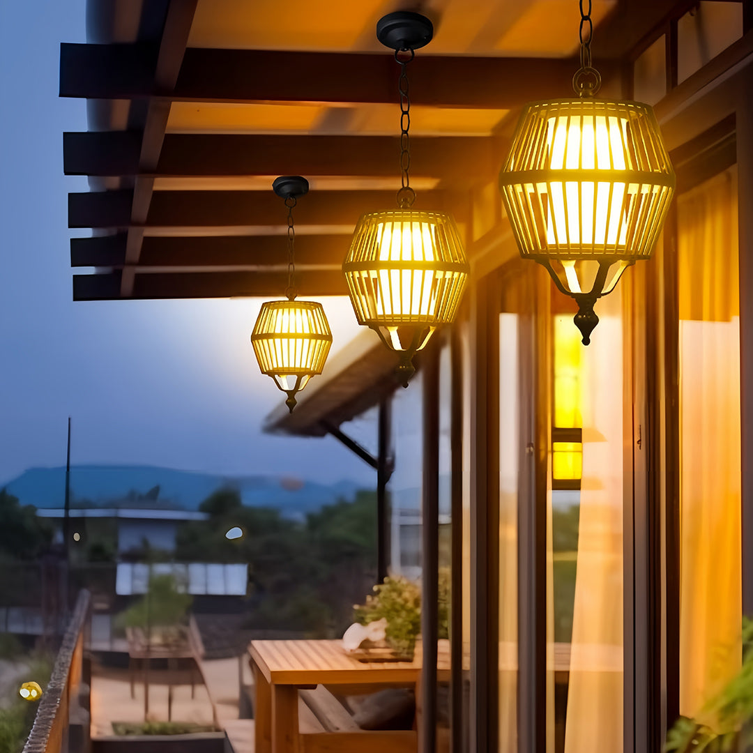 Woven rattan japanese lantern pendant light illuminating an outdoor dining area on a wooden deck at dusk.