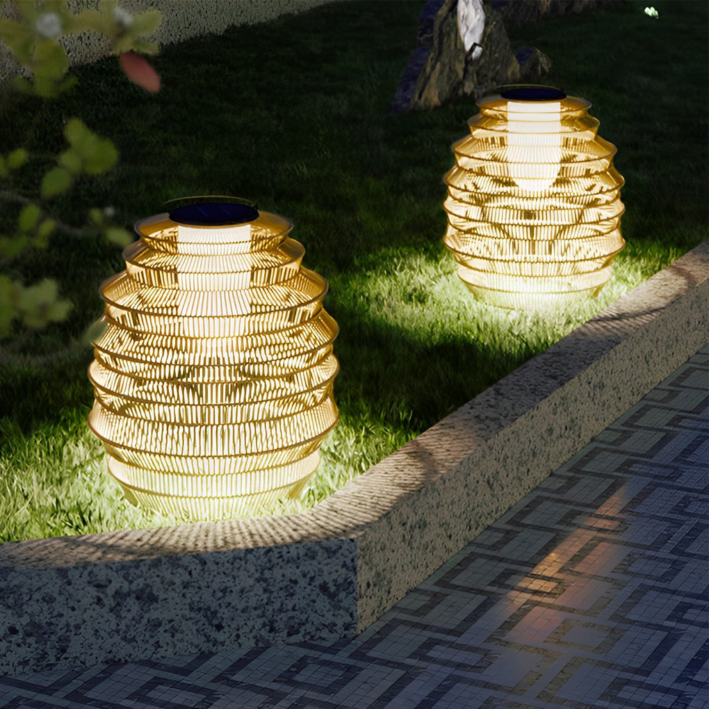 Rattan outdoor lantern with a modern design, illuminating a garden pathway.