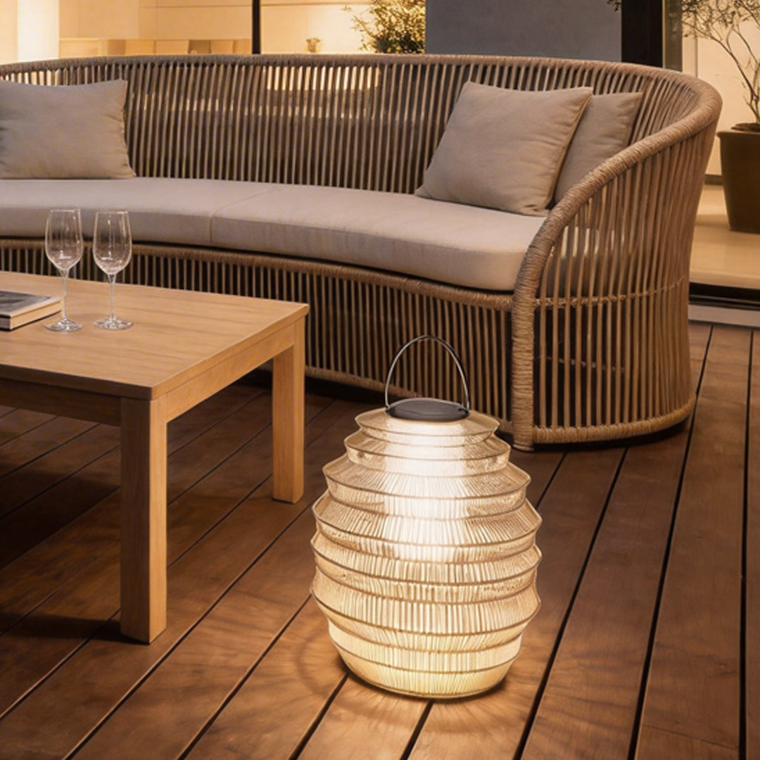 Rattan outdoor lantern with a woven design, providing warm illumination on a patio table.