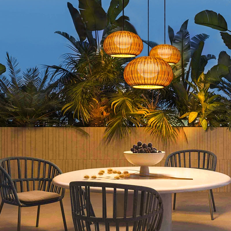 Rattan outdoor pendant light providing ambient lighting for an outdoor dining area.
