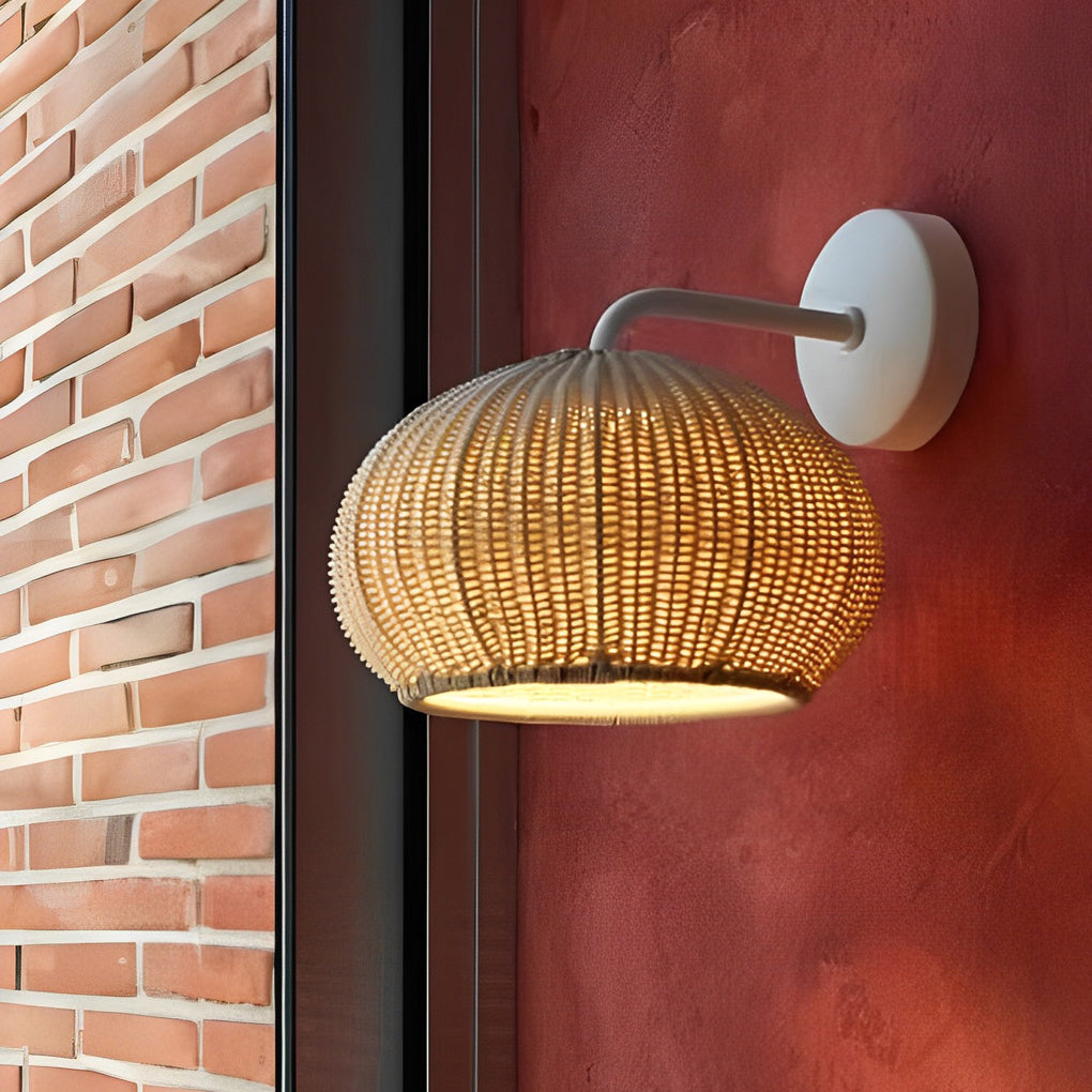 Rattan outdoor pendant light mounted on a brick wall, casting a soft glow.